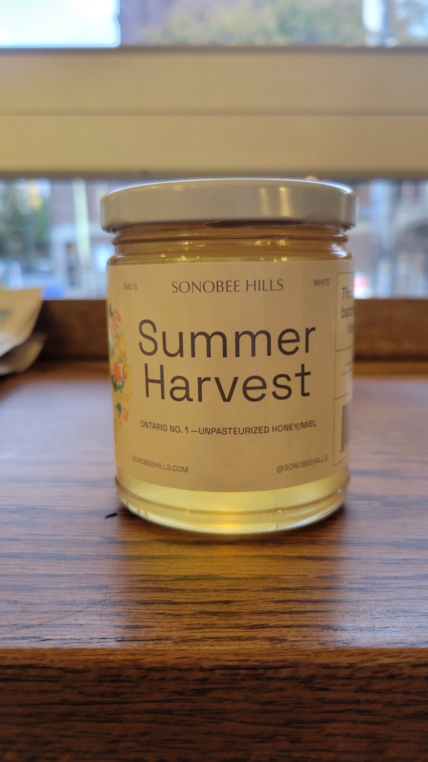 Jar of 'Summer Harvest' honey by Sonobee hills on a wooden surface
