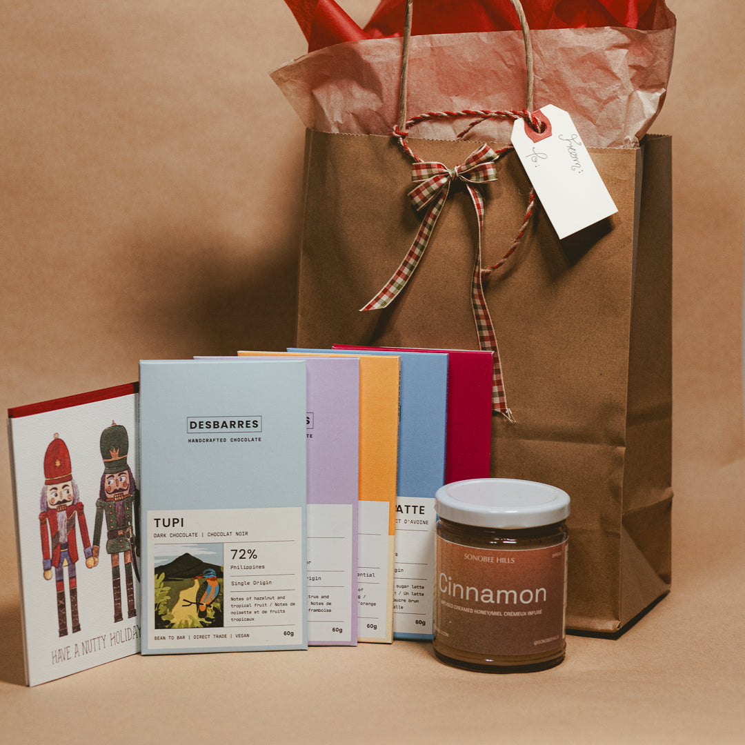 Gift bag with a cinnamon honey jar and chocolate bars on a brown background