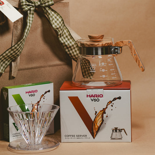 Hario V60 coffee server and filter with packaging on a brown background