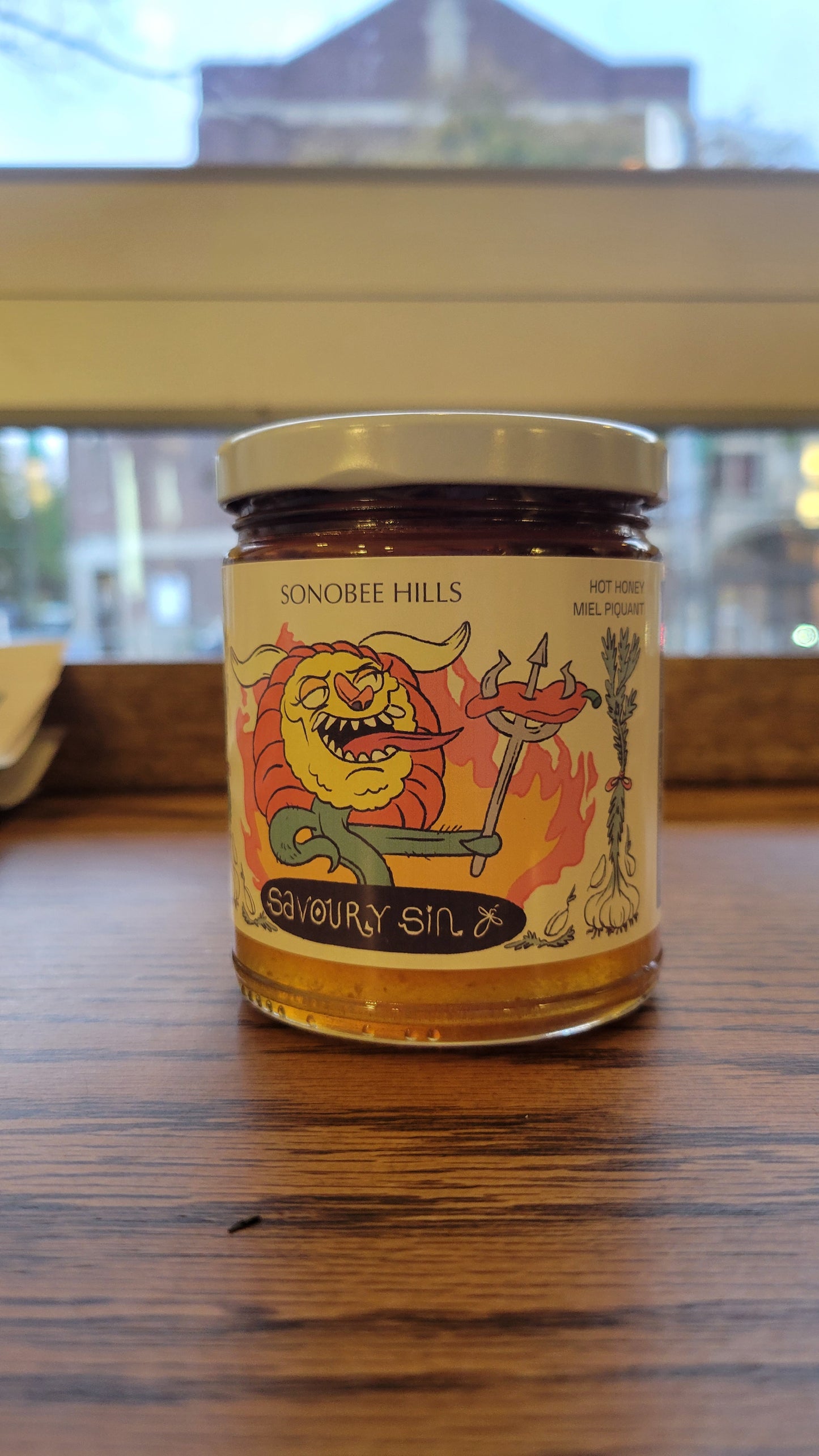 Jar of spicy honey on a wooden surface with a blurred background